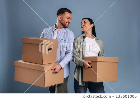 Against blue wall, with boxes, moving. Man and woman are in the studio Against blue wall, with boxes, moving. Man and woman are in the studio 135601006