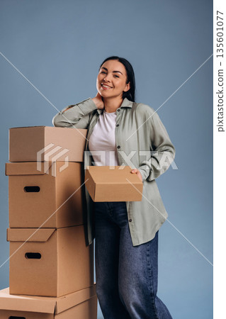 Standing with the boxes, moving. Beautiful woman is against background Standing with the boxes, moving. Beautiful woman is against background 135601077