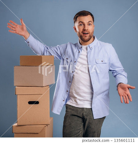 Look at those boxes, hands to the sides, facial expression. Handsome man is against background Look at those boxes, hands to the sides, facial expression. Handsome man is against background 135601111