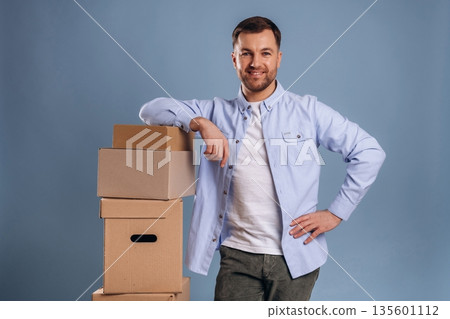 Ready to move, with boxes. Handsome man is against background Ready to move, with boxes. Handsome man is against background 135601112