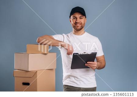 Worker of delivery service, with boxes. Handsome man is against background Worker of delivery service, with boxes. Handsome man is against background 135601113