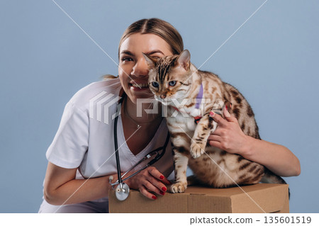 Smiling, cheerful facial expression. Female veterinarian is with Bengal cat 135601519