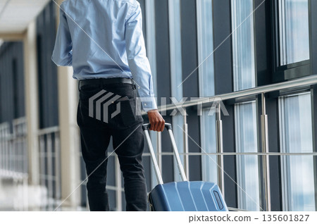 Walking with suitcase. Male tourist is in the airport corridor Walking with suitcase. Male tourist is in the airport corridor 135601827