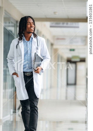 Walking forward. Young male black doctor is in the corridor 135601861