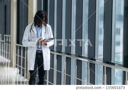 Young male black doctor is in the corridor Young male black doctor is in the corridor 135601873