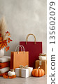 Autumn gift display with bags and pumpkins on marble surface 135602079