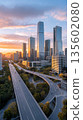 Sunset over modern city skyline with highways and skyscrapers 135602080