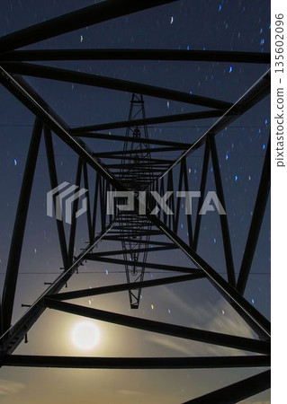 Power line tower at night with moon and star trails Power line tower at night with moon and star trails 135602096