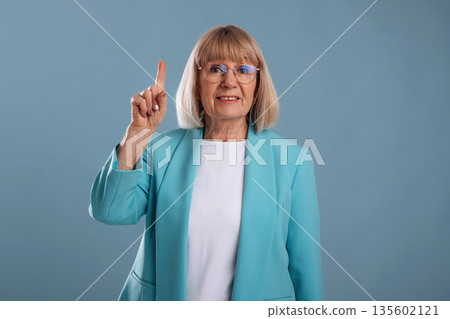 Showing up by finger. Senior woman is against background 135602121