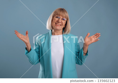 Hands to the sides, smiling. Senior woman is against background Hands to the sides, smiling. Senior woman is against background 135602123
