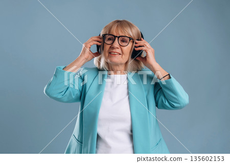 Listening to music, enjoying. Senior woman is against background Listening to music, enjoying. Senior woman is against background 135602153