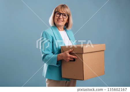 Moving conception, holding box. Senior woman is against background 135602167