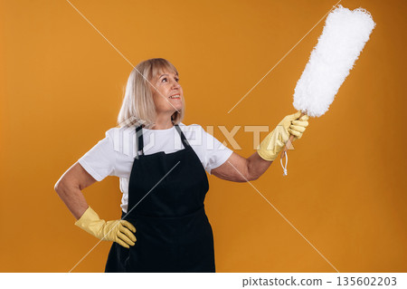 Ready to clean the house. Senior housewife is standing against background Ready to clean the house. Senior housewife is standing against background 135602203