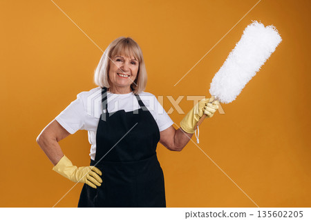 Ready to clean the house. Senior housewife is standing against background Ready to clean the house. Senior housewife is standing against background 135602205