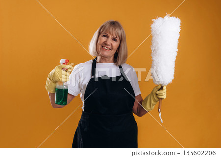 Ready to clean the house. Senior housewife is standing against background 135602206