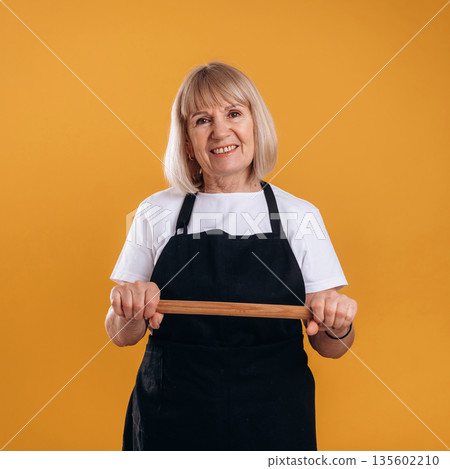 Senior housewife is standing against background Senior housewife is standing against background 135602210