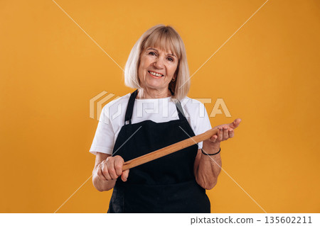 Senior housewife is standing against background 135602211