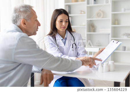 Female doctor reviewing medical document with senior male patient during consultation Female doctor reviewing medical document with senior male patient during consultation 135604229