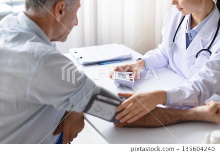 Female doctor measuring blood pressure of senior male patient using digital monitor Female doctor measuring blood pressure of senior male patient using digital monitor 135604240