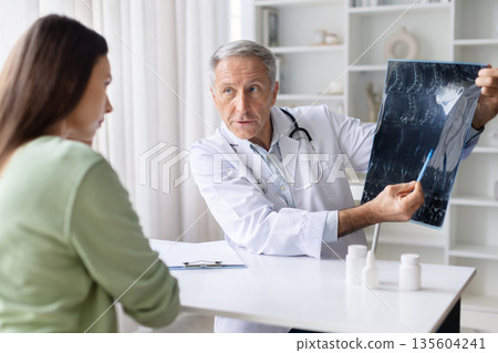 Senior male doctor explaining medical scan results to female patient during consultation Senior male doctor explaining medical scan results to female patient during consultation 135604241