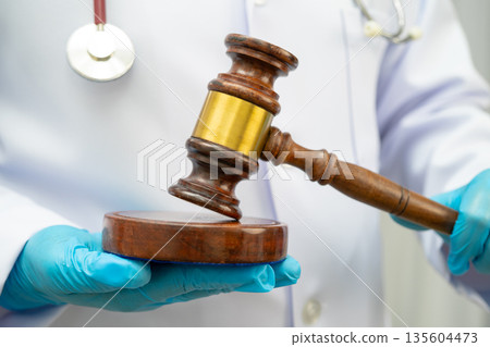 Asian doctor holding court hammer for and crime law justice, forensic medicine. 135604473