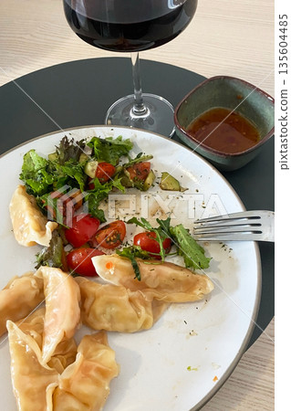 Delicious Dumplings with Fresh Salad and Red Wine Pairing 135604485