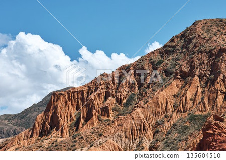 Red rock mountain in Kyrgyzstan with blue sky and white cumulus clouds 135604510