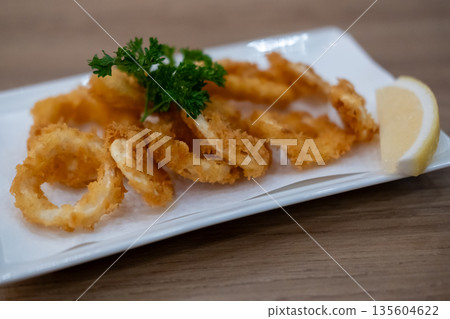 Close-up photo of Fried Squid or Calamari with lemon served on plate. Close-up photo of Fried Squid or Calamari with lemon served on plate. 135604622