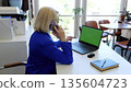 Caucasian woman works at office desk on laptop with green chroma key screen media technologies. In office setting female types on laptop with green chroma key screen digital work environment. 135604723