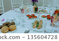 Elegant table arrangement displaying gourmet canapes, red caviar rolls, crisp vegetables, and artisan bread, preparing for high end catering service 135604728