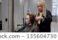 Hairdresser carefully drying and styling a client's hair in a cozy salon, creating a trendy look with expertise and precision 135604730