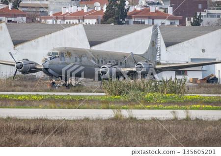 Abandoned propeller airplane resting on overgrown airfield Abandoned propeller airplane resting on overgrown airfield 135605201