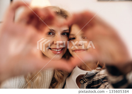 Hands with love gesture. Mother and daughter are together in domestic room 135605384