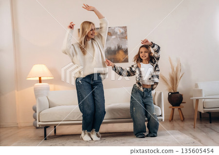 Standing and dancing, fun. Mother and daughter are together in domestic room 135605454