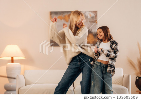 Carefree, dancing and having fun. Mother and daughter are together in domestic room Carefree, dancing and having fun. Mother and daughter are together in domestic room 135605509