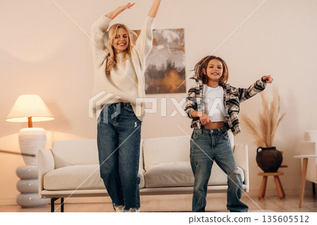 Carefree, dancing and having fun. Mother and daughter are together in domestic room 135605512