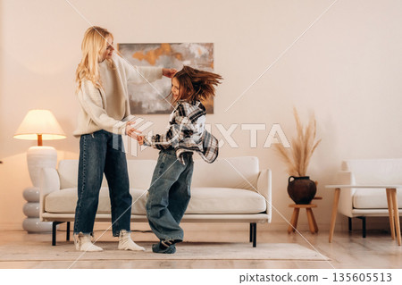 Carefree, dancing and having fun. Mother and daughter are together in domestic room Carefree, dancing and having fun. Mother and daughter are together in domestic room 135605513