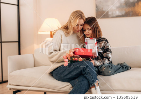 In domestic room, celebration of mother's day with gifts. Woman and her daughter In domestic room, celebration of mother's day with gifts. Woman and her daughter 135605519