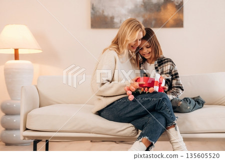 In domestic room, celebration of mother's day with gifts. Woman and her daughter In domestic room, celebration of mother's day with gifts. Woman and her daughter 135605520