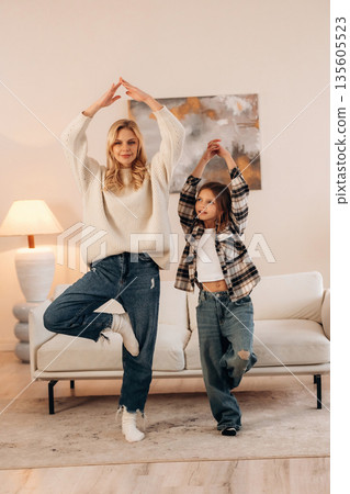Standing on one leg, sport and yoga. Mother and daughter are together in domestic room 135605523