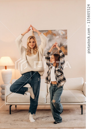 Standing on one leg, sport and yoga. Mother and daughter are together in domestic room 135605524