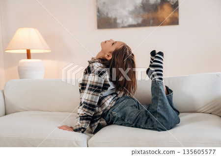 Fun on the sofa. Cute little girl is in the domestic room alone Fun on the sofa. Cute little girl is in the domestic room alone 135605577