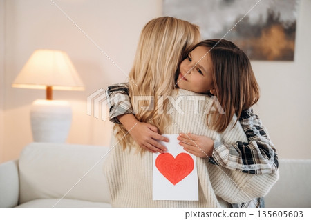Sweet little hand drawn heart, mother's day. Woman and her daughter are together in domestic room Sweet little hand drawn heart, mother's day. Woman and her daughter are together in domestic room 135605603