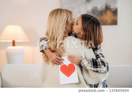 Sweet little hand drawn heart, mother's day. Woman and her daughter are together in domestic room Sweet little hand drawn heart, mother's day. Woman and her daughter are together in domestic room 135605604