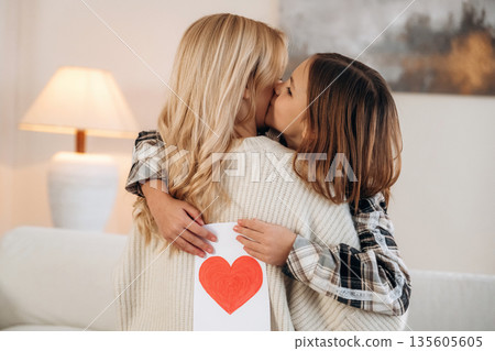 Sweet little hand drawn heart, mother's day. Woman and her daughter are together in domestic room Sweet little hand drawn heart, mother's day. Woman and her daughter are together in domestic room 135605605