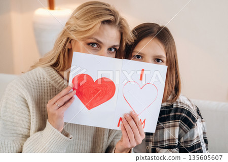 Sweet little hand drawn heart, mother's day. Woman and her daughter are together in domestic room Sweet little hand drawn heart, mother's day. Woman and her daughter are together in domestic room 135605607