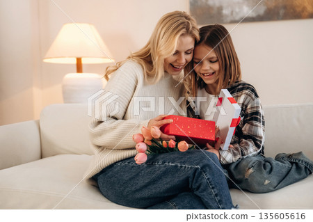 What's in the box. Mother's day. Woman and her daughter are together in domestic room What's in the box. Mother's day. Woman and her daughter are together in domestic room 135605616