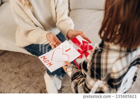 Cute moment, mother's day presents. Woman and her daughter are together in domestic room Cute moment, mother's day presents. Woman and her daughter are together in domestic room 135605621