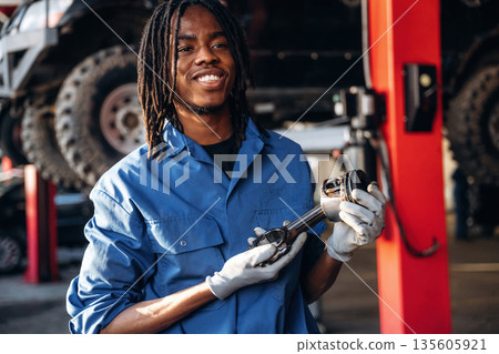 Automobile part in hands. Male mechanic is with car in garage Automobile part in hands. Male mechanic is with car in garage 135605921