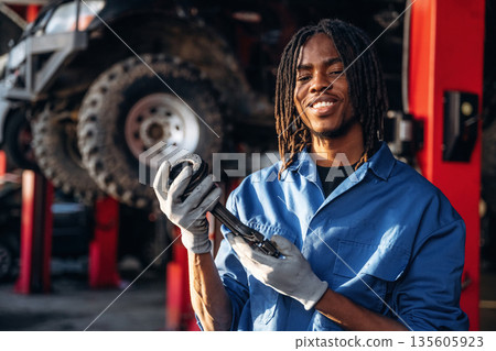 Automobile part in hands. Male mechanic is with car in garage 135605923